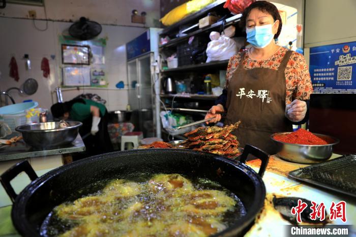 圖為平安驛·河湟民俗文化體驗(yàn)地內(nèi)的商戶炸干板魚(yú)。　薛蒂 攝